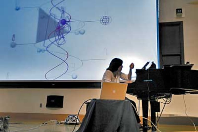 Elaine Chew plays the piano while a computer analyzes her rhythms and splashes graphics on a screen behind her during a concert at Drexel University, part of the 9th International Conference for Music Information Retrieval. (Eric Mencher/Inquirer)