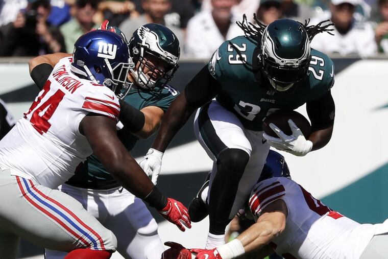 Eagles running back LeGarrette Blount leaps over New York Giants middle linebacker Calvin Munson as Eagles tight end Brent Celek blocks New York Giants defensive tackle Dalvin Tomlinson on Sunday.