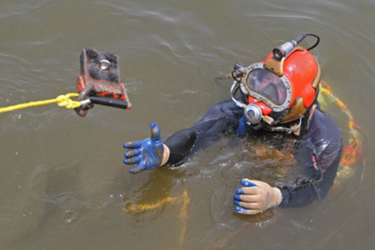 Andrew Yoder reaches for a magnet to bring up more debris from the Delaware. (Michael Bryant / Staff Photographer)