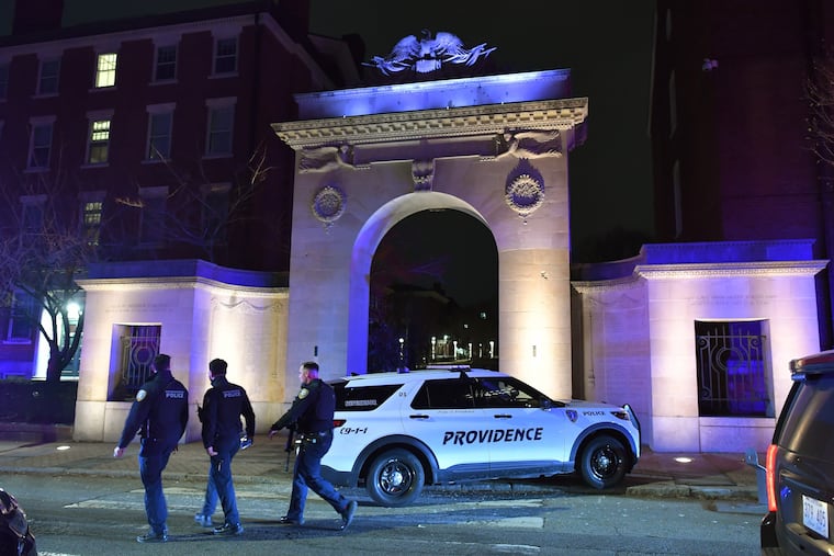Law enforcement officials walk near an entrance to Brown University in Providence, R.I., on Saturday, during the investigation of a shooting.