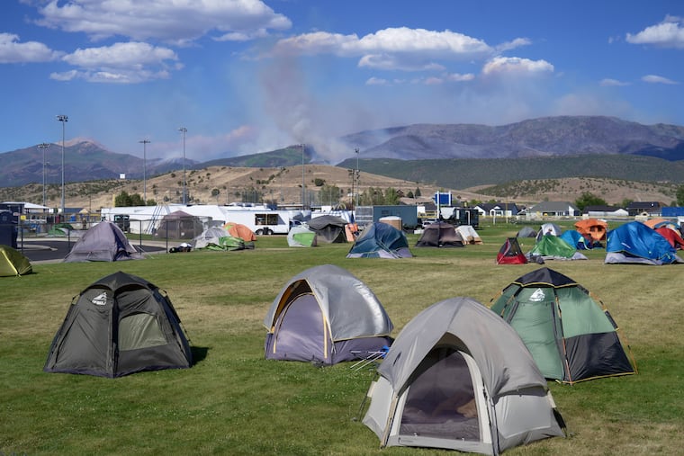 Firefighter tents sit across an elementary school lawn with the Cottonwood Fire in the background, in Beaver, Utah on Saturday, June 27, 2026.