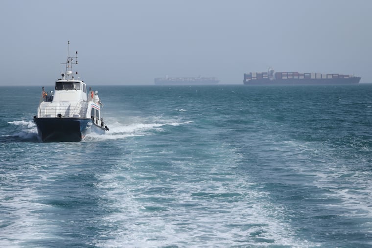 A patrol boat moves through the water as cargo ships sit at anchor in the Strait of Hormuz off Bandar Abbas, Iran, Saturday.
