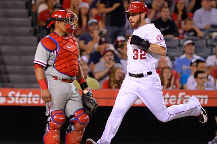 Josh Hamilton, right, scores on a single by Howie Kendrick as Philadelphia Phillies catcher Carlos Ruiz looks on during the sixth inning of a baseball game, Wednesday, Aug. 13, 2014, in Anaheim, Calif. (Mark J. Terrill/AP)