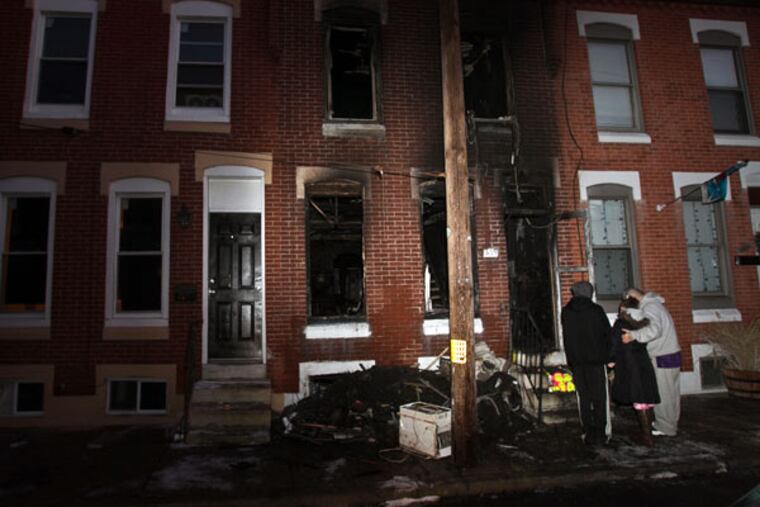 Family members of the two who died stand in front of the rowhome on the 400 block of Daly Street in South Philadelphia on Thursday, Jan. 29, 2015. From left, nephew David Vogel, his cousin Christina Andrews and her husband, Noel Rivera. They set up a makeshift memorial on the steps of the home. ( ALEJANDRO A. ALVAREZ / STAFF PHOTOGRAPHER )