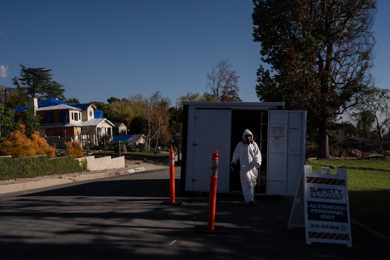 A worker in protective gear exits a storage container at a cleanup site, Dec. 3, 2025, months after the Eaton Fire, in Altadena, Calif.