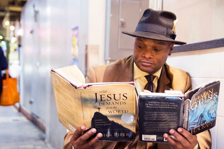 Milton Barham spends his lunch break in Reading Terminal Market, reading two books at the same time. Barham first realized that he could read two books simultaneously when he was in 9th grade. Since then, he has been reading 800-900 books a year. He has read these two books -- "The Man God Uses" by Henry and Tom Blackbay, and "What Jesus Demands From The World" by John Piper -- about 10 times each. (RACHEL WISNIEWSKI / Staff Photographer)