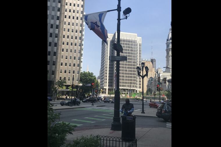 Unidentified man with what appeared to be a paint gun under the vandalized Israeli flag Tuesday afternoon on the Benjamin Franklin Parkway.
