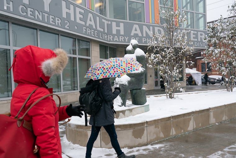 Pedestrians make their way through the snow in front of the South Philadelphia Library in 2019. Some Philly libraries have been activated as warming centers during the recent cold snap.