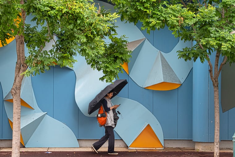 A pedestrian shields from the rain with an umbrella last week.