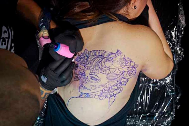 Christina Benavides gets a Catrina Day of the Dead tattoo designed by Oscar " The Bear" at the 16th annual Philadelphia Tattoo Convention at the Convention Center. ( RON TARVER / Staff Photographer ) February 2, 2014