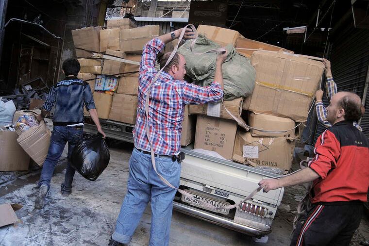 Merchants removing their wares from a marketplace in Aleppo, Syria. Thousands of business owners have moved abroad in the last year, to Lebanon, Turkey, and other places.