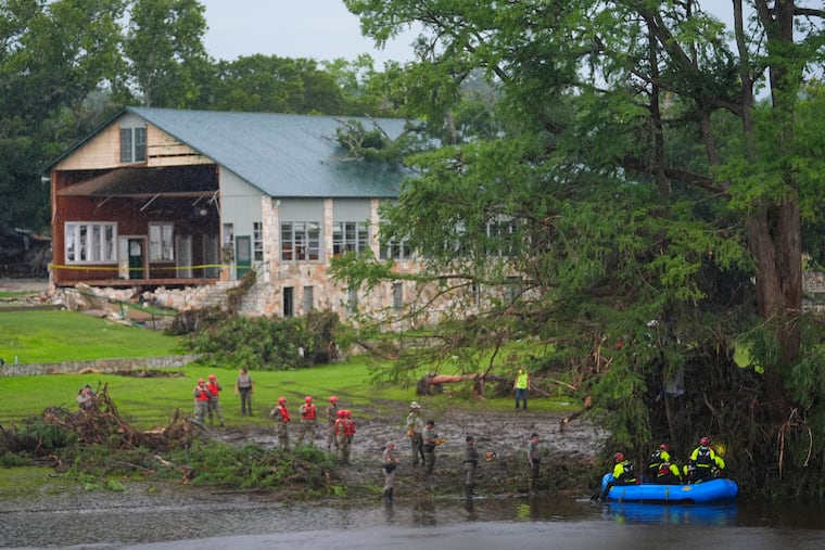 Rescue workers are seen on land and on a boat as they search for missing people near Camp Mystic along the Guadalupe River on July 6, 2025, in Hunt, Texas.