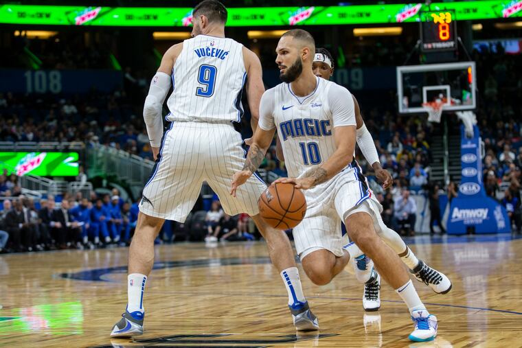 Orlando Magic guard Evan Fournier (10) dribbles by center Nikola Vucevic (9) and Philadelphia 76ers guard Josh Richardson during the first half of Friday's game at the Amway Center.