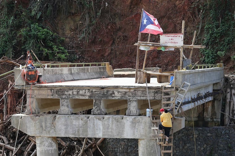 A man climbs a ladder to the Campamento de los Olvidados, ( The camp of the Forgotten ) on the Rio Arecibo in Utuado Puerto Rico, Thursday Nov. 2, 2017. Hurricane Maria washed out the bridge requiring people to walk across the river and climb a wooden ladder to reach the top of the bridge.