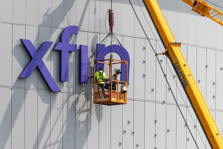 Workers putting up the Xfinity Mobile Arena signage at the Wells Fargo Center in Philadelphia, on Thursday, August 14, 2025.