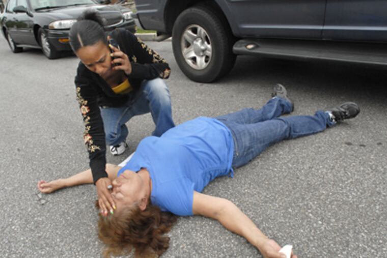 Overwhelmed by grief, Jose Feliciano’s grandmother Luisa Diaz collapses in the street in Camden’s Baldwin Run neighborhood. Feliciano’s sister Crystal Mendez tried to help her. (April Saul / Staff Photographer)