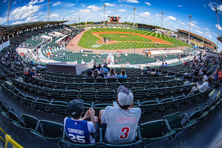 Fans watch from the outfield lawn Sunday, as the Phillies opened their exhibition season against the Detroit Tigers at Joker Marchant Stadium in Lakeland, Fla.