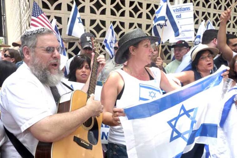 Marc Pevar (left), co-president of the Philadelphia chapter of the Zionist Organization of America, leads Israel supporters in a traditional song in Hebrew. About 250 people rallied near the Israeli consulate at 19th Street and J.F.K. Boulevard Friday to counter criticism in the wake of a commando raid Monday that killed nine activists.