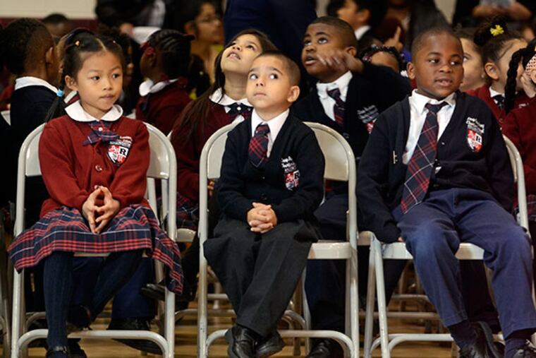 LEAP Academy University Charter School first graders Angelina Le (from left), Angel Rivera and Amir Reason-Dallas wait with classmates for start of induction ceremonies and the awarding of ceremonial scholarships to students, including 160 in first through third grade, November 20, 2013. The scholarships are contingent on the student maintaining a 3.5 and getting into Rutgers. The scholarship has been offered to graduating seniors since 1997 but this is the first year it's being introduced to the younger grades. ( TOM GRALISH / Staff Photographer )