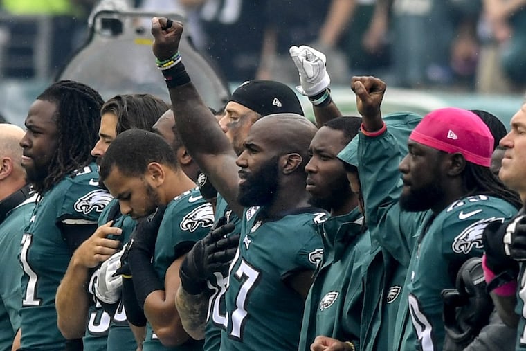 Eagles’ Malcolm Jenkins (center) and some teammates raise their right fist during the national anthem before the Arizona game.