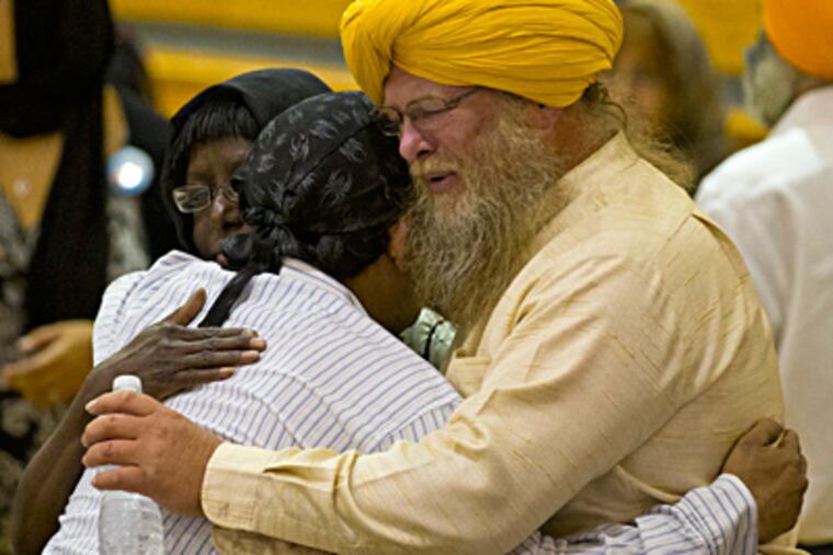 Mourners console one another at a memorial service for the six victims of the temple shooting in Oak Creek, Wis. Some said the death toll could have been much higher. JEFFREY PHELPS / AP