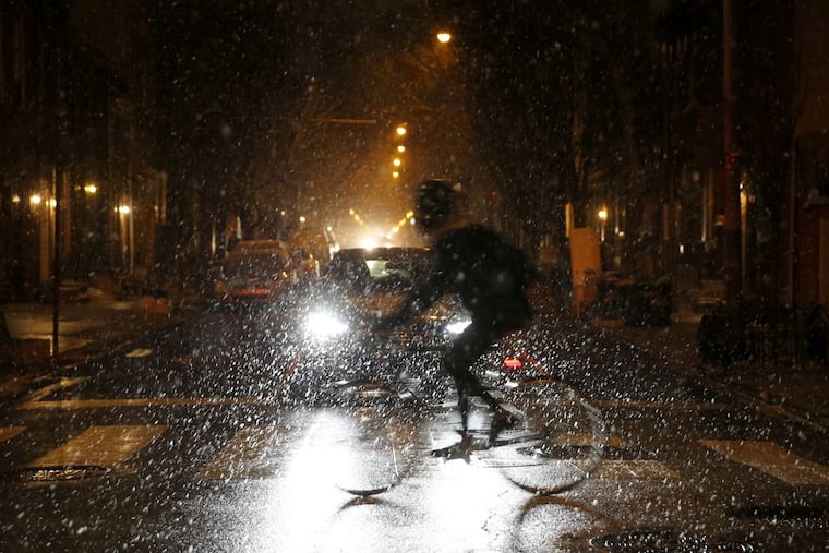 A cyclist rides across South 10th Street at Lombard Street as snow falls in Philadelphia in January. Snowfall is expected Saturday.
