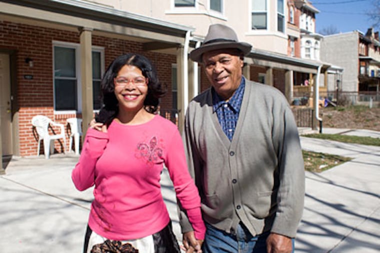Warren Harrison, 82, and his companion Khadijah Abdullah, 42, walk in front of rowhouses built on city-owned land in the 1900 block of Venango Street in North Philadelphia. (Ed Hille / Staff Photographer)