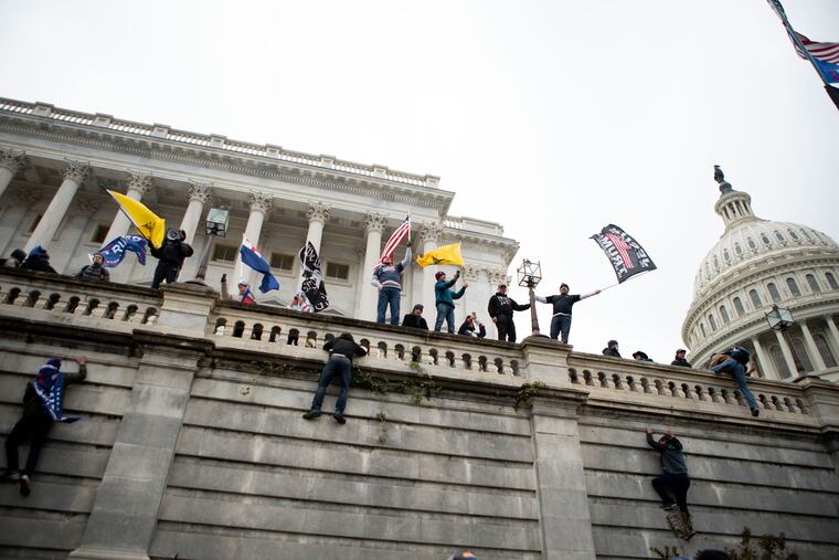 Supporters of President Donald Trump climb the west wall of the the U.S. Capitol on Jan. 6.