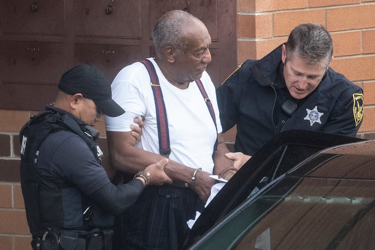Bill Cosby is escorted by police in handcuffs as he exits the Montgomery County Correctional Facility in Norristown on Tuesday.