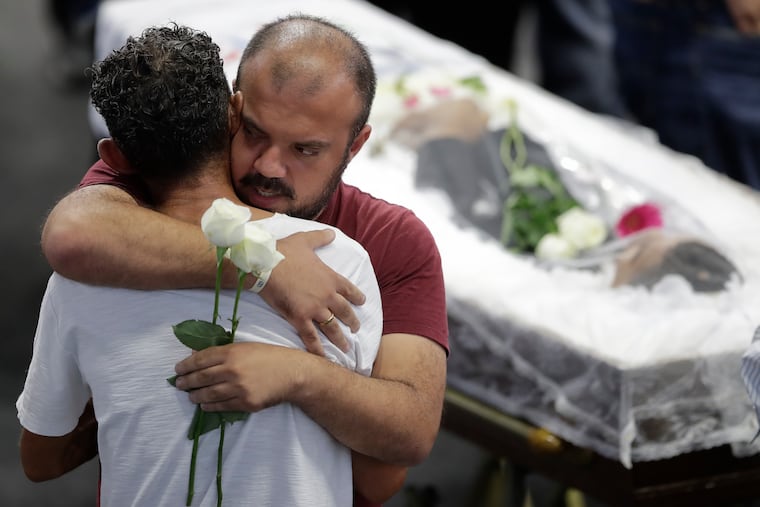 Relatives embrace next to the coffin containing the remains of 17-year-old Claiton Antonio Ribeiro, a victim of the mass shooting at the Raul Brasil State School, in Suzano, Brazil, Thursday, March 14, 2019. (AP Photo/Andre Penner)
