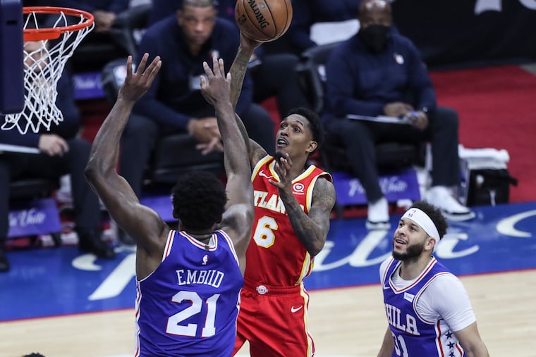 The Hawks' Lou Williams shoots between Sixers Joel Embiid and Seth Curry during the fourth quarter of Game 5.