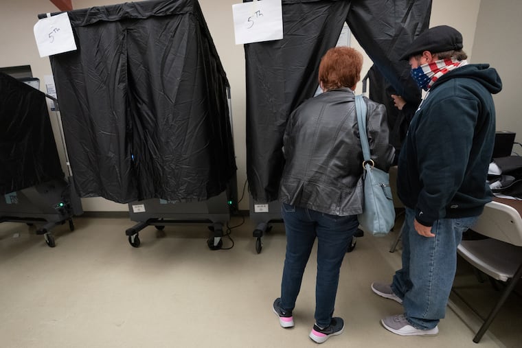 Danny D'Agostino (right) machine inspector, assists a voter at the polling place at Barry Playground in South Philadelphia on Election Day last year.