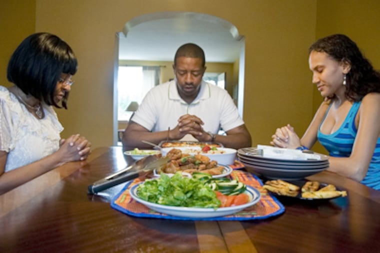 City Assistant Managing Director Adé Fuqua dines with his mother Renee, left, and wife Holremin, right, at his mom's house on Sunday afternoon. Fuqua works with the city's PhillyRising initiative in South Philadelphia. ( ABI REIMOLD / STAFF PHOTOGRAPHER )