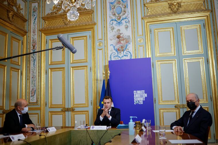 French President Emmanuel Macron (center), with French Foreign Minister Jean-Yves Le Drian (left) and President of the French Constitutional Council Laurent Fabius, speaks during the Climate Ambition Summit 2020 in December.