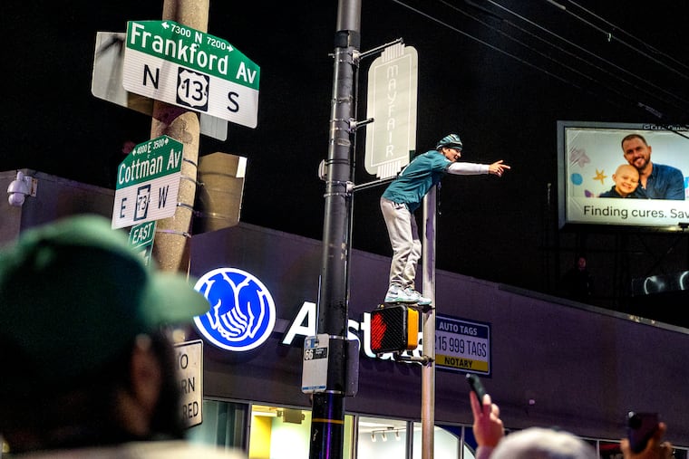 A fan climbs a pole at Cottman and Frankford Avenues in Mayfair following the Eagles’victory over the San Francisco 49ers in the NFC Championship.