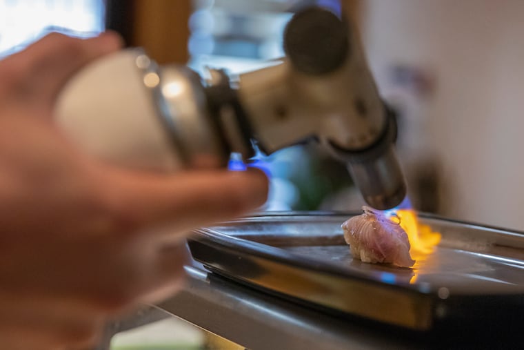 Sam Lin, owner and chef of Sakana, torching fish at his counter in Queen Village.