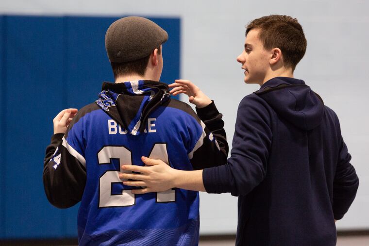 John Burke III (right) walks through the gym with his autistic little brother, Tony, at Holy Ghost Academy in Bensalem, during a special needs basketball clinic created entirely by big bro for little bro.