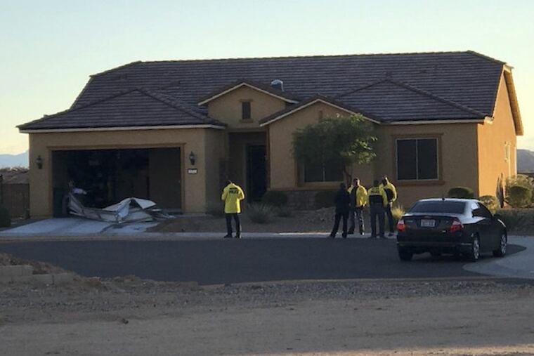 In this photo provided by the Mesquite, Nev., Police Department, police personnel stand outside the home of Stephen Paddock in Mesquite.