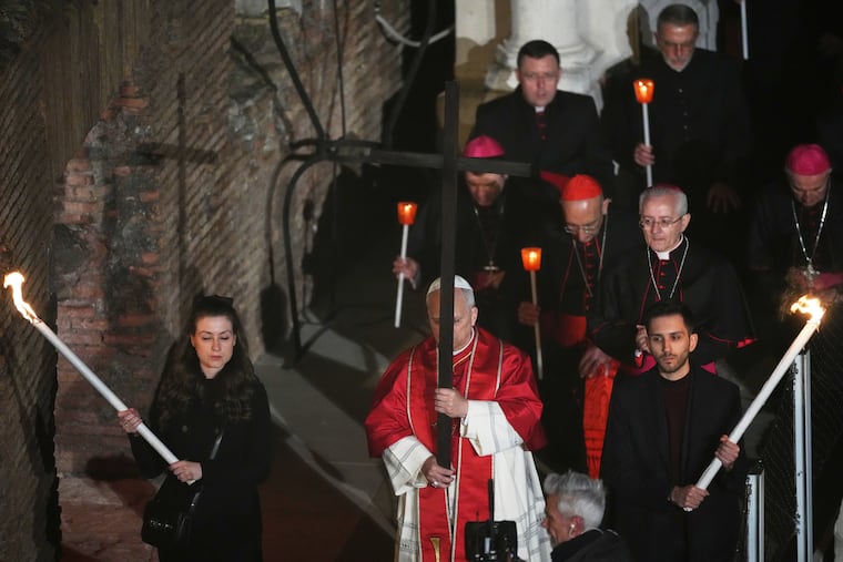 Pope Leo XIV carries a wooden cross during the Way of the Cross procession at the Colosseum on Good Friday in Rome.