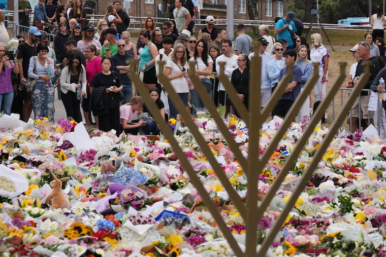 A Hanukkah menorah stands by a floral tribute as people gather to pay their respects near the Bondi Pavilion at Bondi Beach on Dec. 16, following Sunday's shooting in Sydney, Australia.