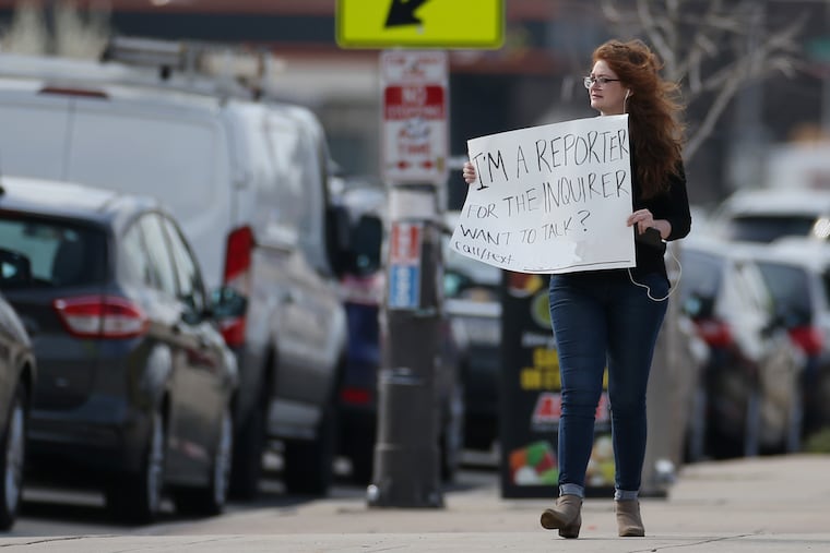 Philadelphia Inquirer reporter Ellie Silverman covers the coronavirus in March — before wearing face masks was standard — with a posterboard asking passing motorists to call or text her if they wanted to talk for a story.