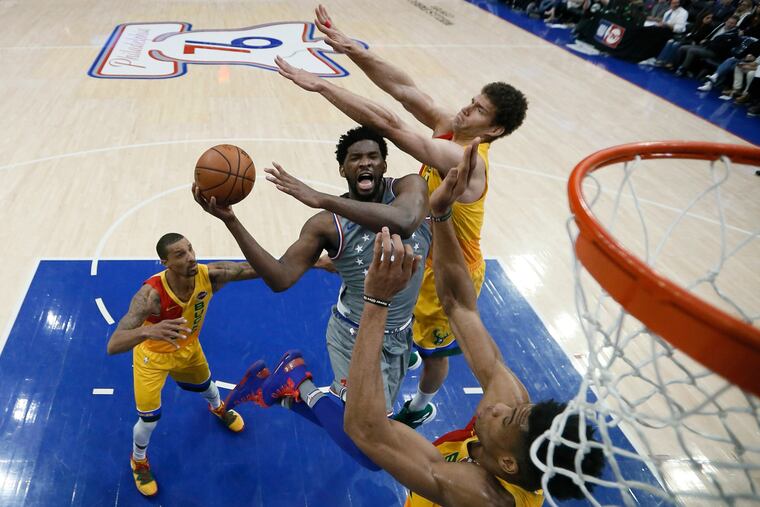 Sixers center Joel Embiid (center) shoots past Milwaukee's Brook Lopez (right) and Giannis Antetokounmpo (under basket) in April.