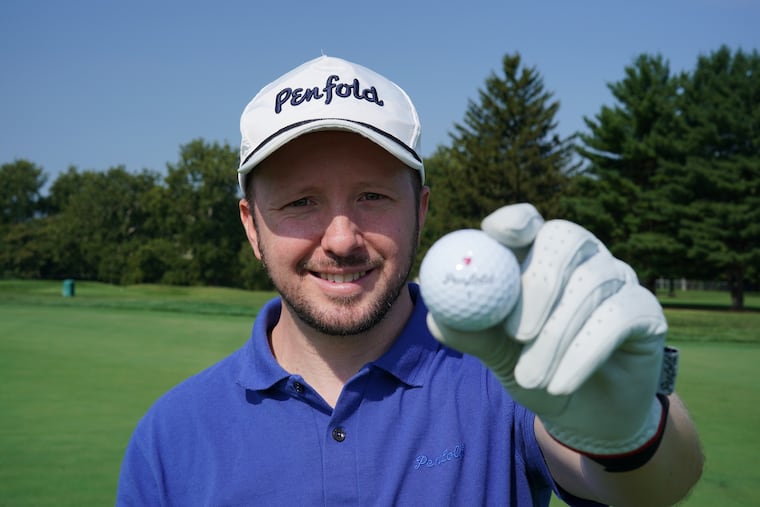 Gavin Perrett holds up a Penfold golf ball on the practice green at the LuLu Country Club in Glenside, Pa.