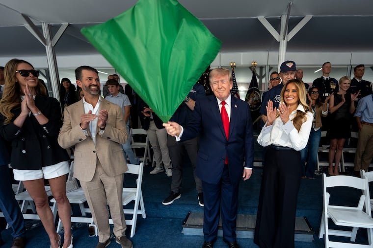 President Donald Trump waves the green flag to start the race alongside first lady Melania Trump (right) and (from left) Bettina Trump and Donald Trump Jr. during the IndyCar Freedom 250 Grand Prix auto race, Aug. 23 in Washington.