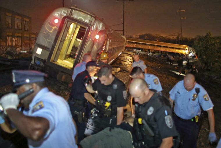 Emergency personnel help a passenger at the scene of a train wreck Tuesday, May 12, 2015, in Philadelphia. An Amtrak train headed to New York City derailed and crashed in Philadelphia. (AP Photo/Joseph Kaczmarek)