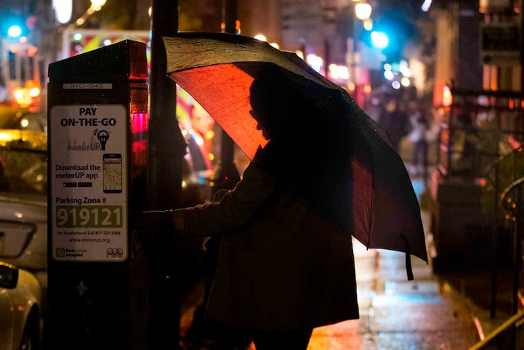 A woman pays for her parking at a kiosk, in the rail along the 1700 block of Locust Street.