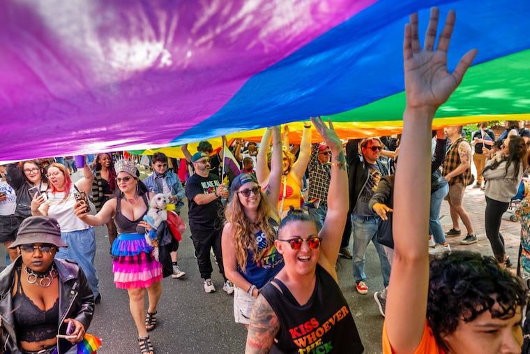 Marchers carry one of the sections of the huge rainbow flag along Walnut Street during the Pride March on Sunday.