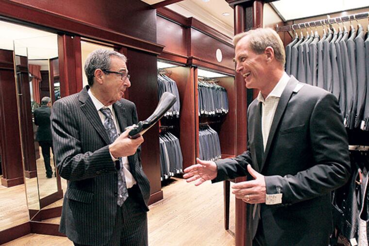 D. Christopher Le Vine, 56, of Bryn Mawr, who is a nephew of the late Grace Kelly, tries on a tuxedo with the help of Howard Eisenberg, left, who has worked as a salesman at Boyds for 48 years. Mr. Eisenberg is calling it quits on Saturday. ( DAVID MAIALETTI / Staff Photographer )