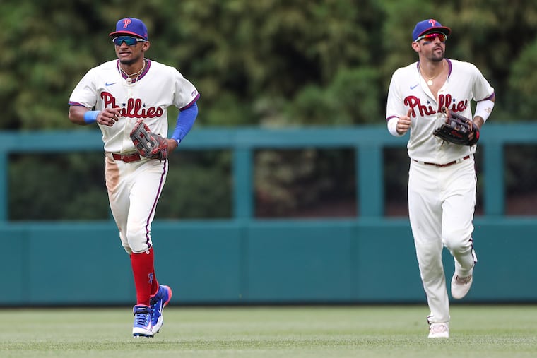 Phillies center fielder Johan Rojas (left) and right fielder Nick Castellanos return to the dugout during a game against the San Diego Padres, the day of Rojas' MLB debut.