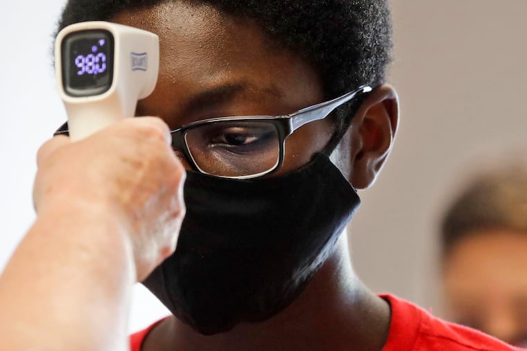 A student wearing a mask has his temperature checked by a teacher before entering a school in Texas in July. (AP Photo/LM Otero)